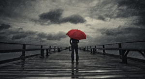 A woman holds a red umbrella on a fishing pier during a storm.